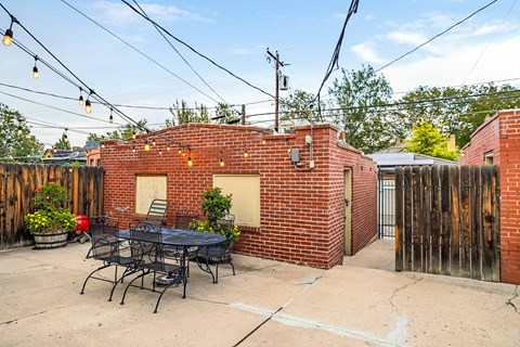 A patio with a table and chairs is surrounded by a brick wall.