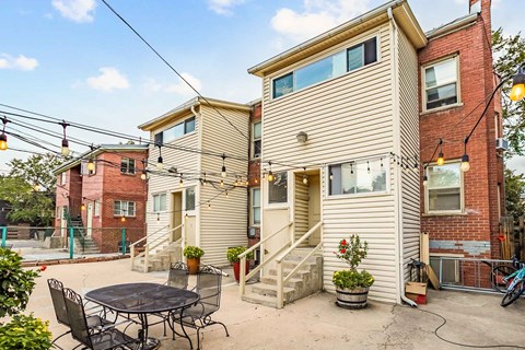 A patio with a table and chairs is in front of a two-story house.