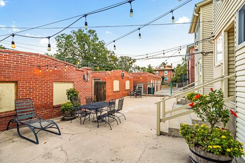 A patio with a table and chairs is surrounded by a brick wall.