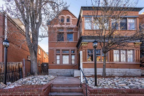 A red brick house with a tree in front.