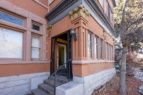 A red brick building with a black door and steps leading up to it.
