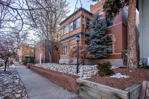A red brick building with a tree in front of it.
