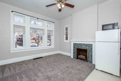 A living room with a fireplace and a ceiling fan.