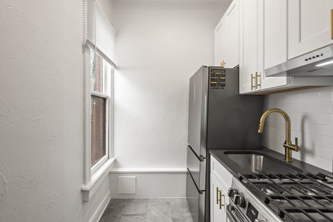 A kitchen with a black fridge and a black stove top.
