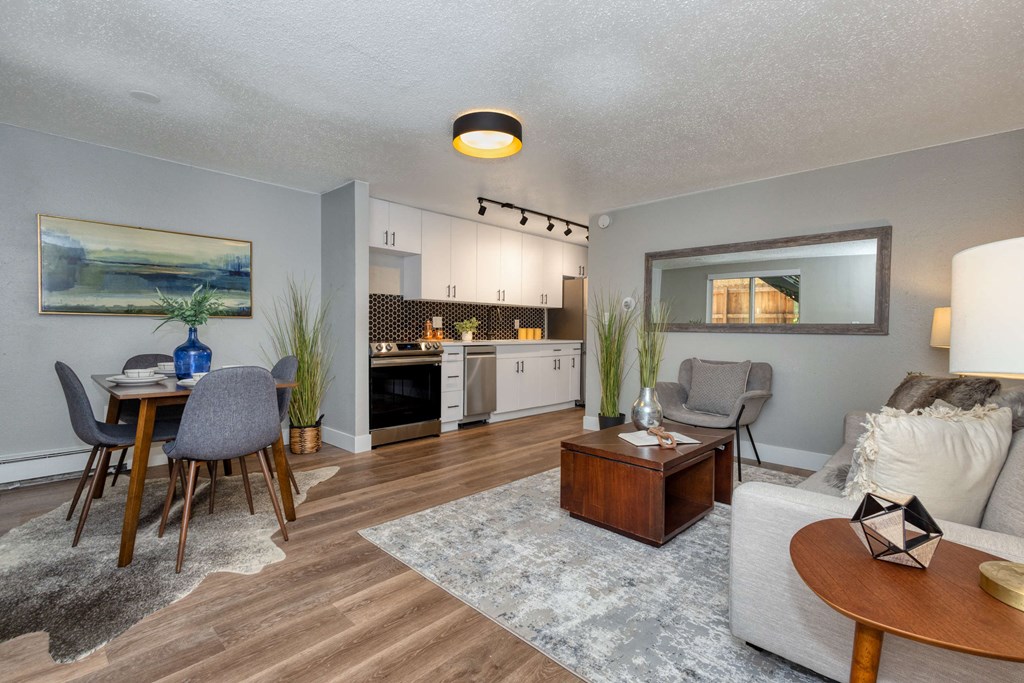 a living room and dining room with a kitchen in the background