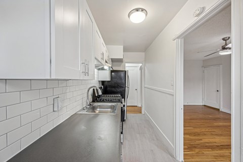 A kitchen with white cabinets and a stainless steel sink.