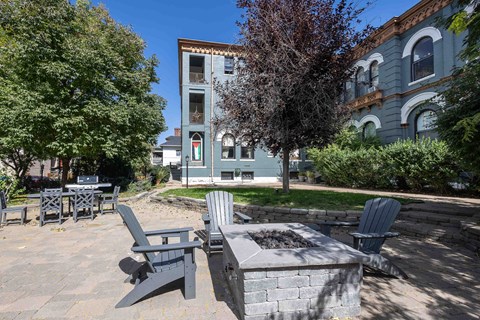 a patio with chairs and a fire pit in front of a building