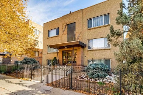 A brown brick house with a black fence in front.