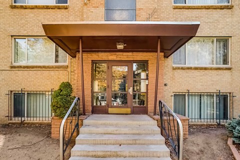 A brick building with a glass door and a metal railing.
