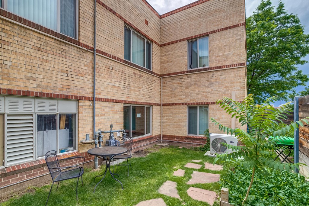 A patio with a table and chairs is surrounded by a brick building.