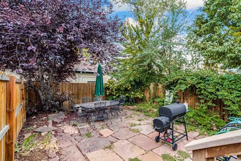 A backyard with a grill and a tree.