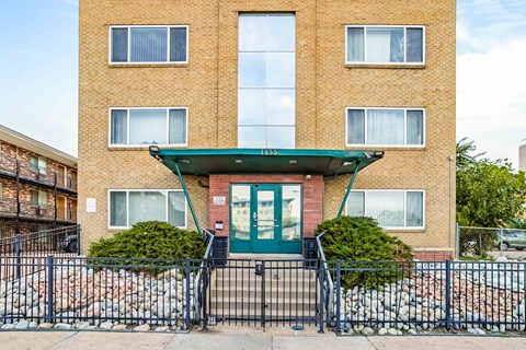 A brick building with a green awning and a black gate in front.
