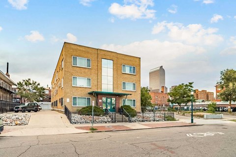 A brown building with a green awning is in front of a tall building.
