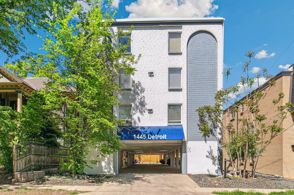 A white building with a blue awning that says 1445 Detroit.