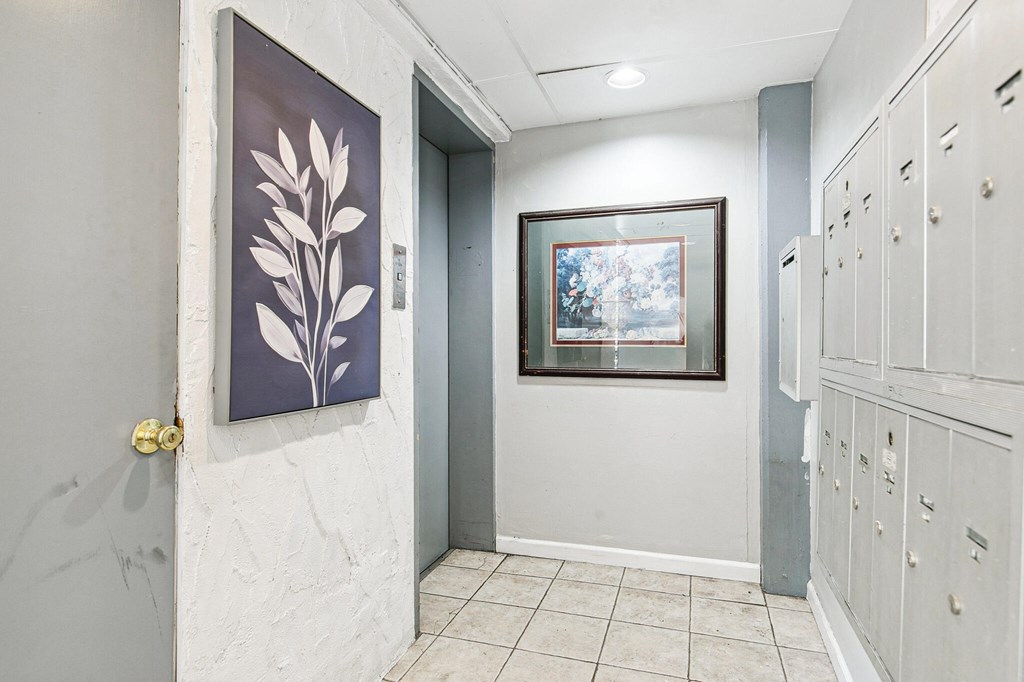 A hallway with a painting of a plant on the wall and a painting of a snowy scene in the background.