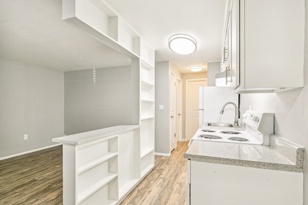 A kitchen with white cabinets and a white sink.