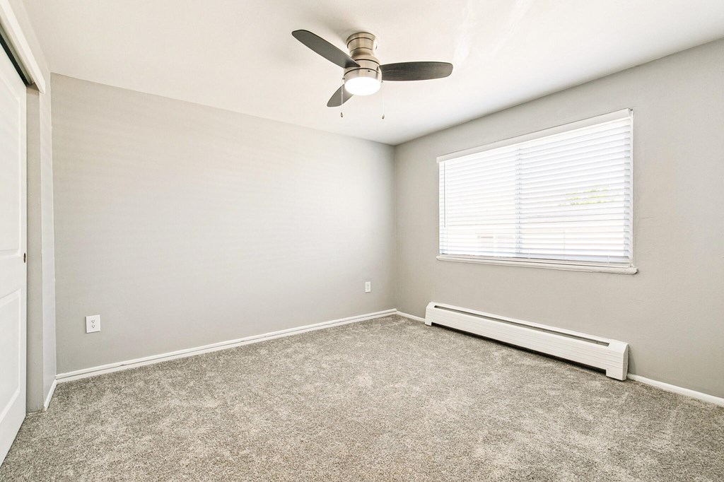 A room with a ceiling fan and a window with blinds.