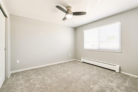 A room with a ceiling fan and a window with blinds.