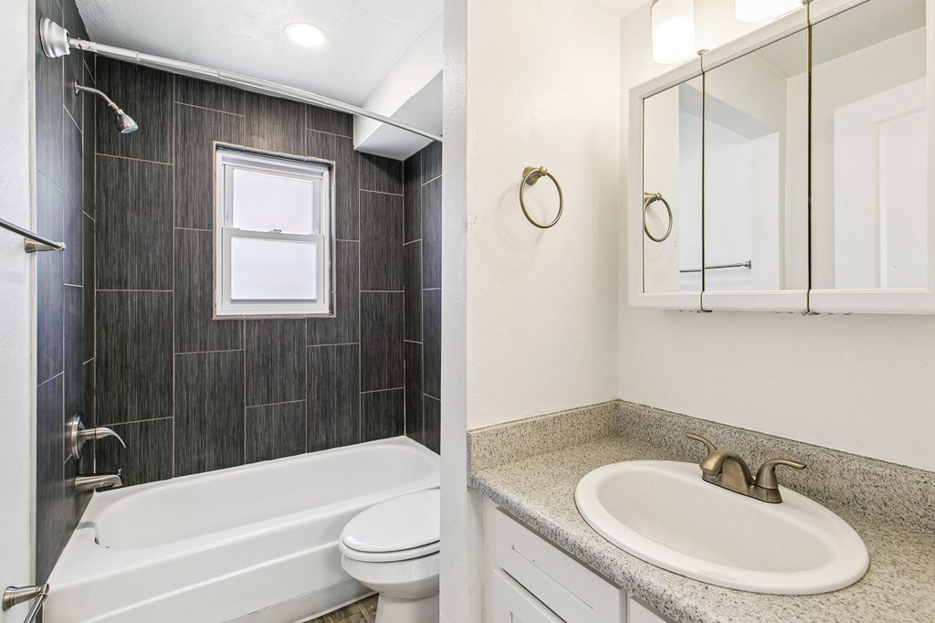 A bathroom with a white tub, sink, and toilet.