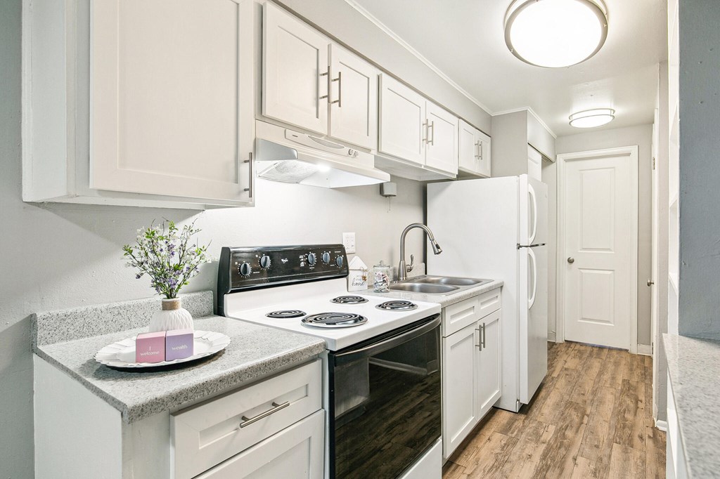 A kitchen with white cabinets and a black stove top.