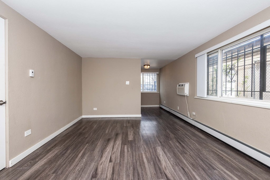 A room with wooden flooring and a window with bars on it.