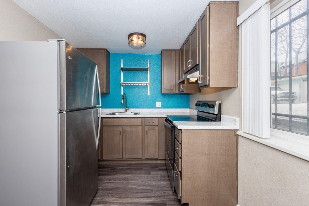 A kitchen with a blue wall and wooden cabinets.