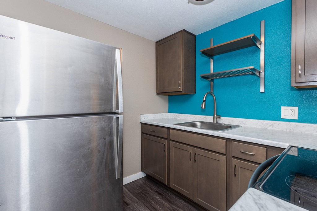 A kitchen with a stainless steel refrigerator and wooden cabinets.