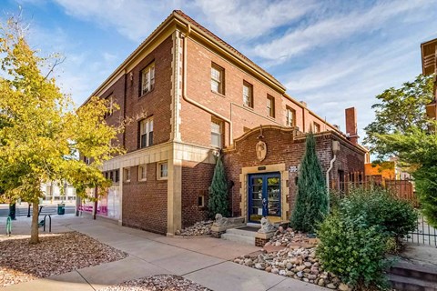 A red brick building with a blue door and windows.