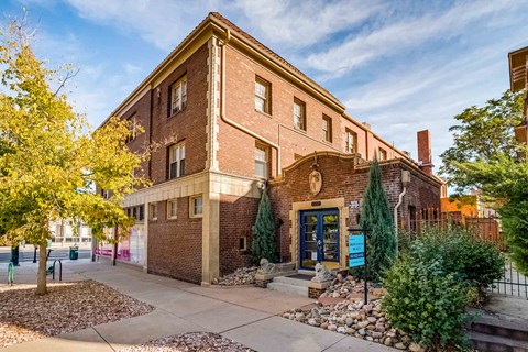 A brick building with a blue door and a sign in front.