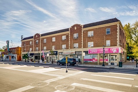 A street view of a building with a pink awning and a crosswalk in front of it.