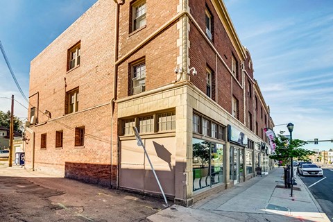 A street view of a red brick building with a closed shop on the ground floor.