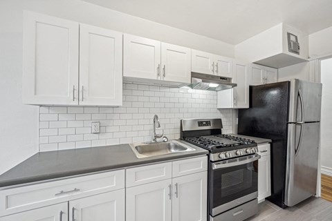 A kitchen with white cabinets and black appliances.