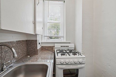 A white gas stove in a kitchen with a window in the background.