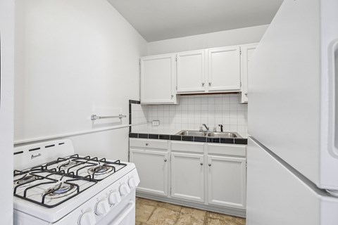 A white stove is in a kitchen with white cabinets.