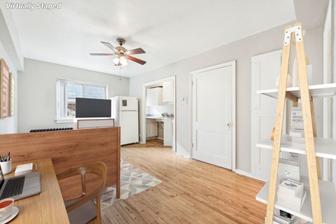 a living room with a desk and a ceiling fan