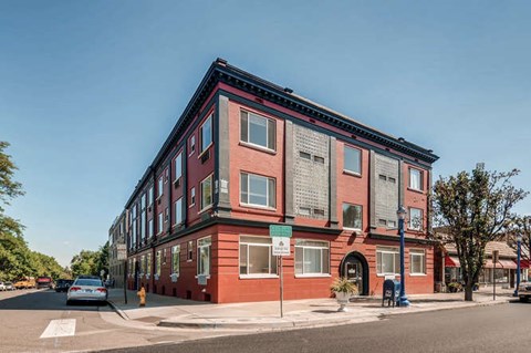 A red brick building with a green sign in front.