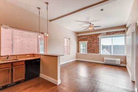 A kitchen with wooden floors and a brick wall.