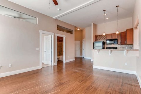 A spacious living room with a kitchen area in the background.
