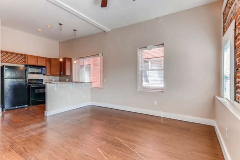A kitchen with wooden floors and a black refrigerator.