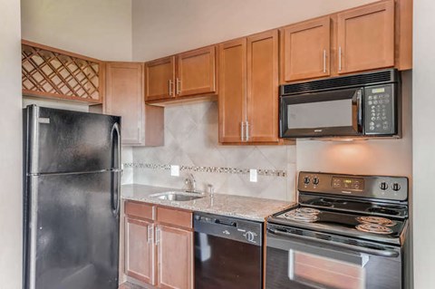A kitchen with a black refrigerator, black microwave, black oven, and black dishwasher.