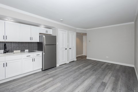 A kitchen with white cabinets and a grey fridge.