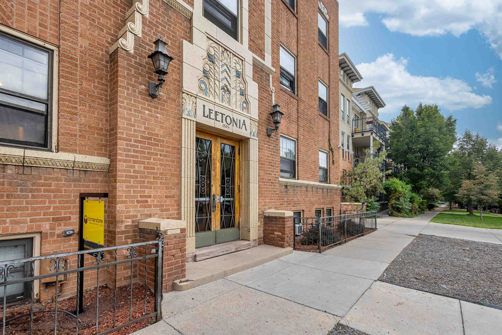a brick building with a yellow door and a sidewalk