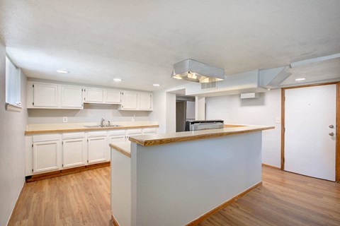 A kitchen with white cabinets and a wooden island.