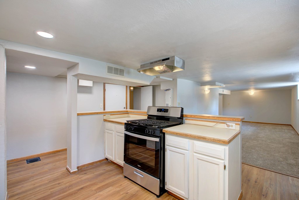 A kitchen with a stove top oven and white cabinets.