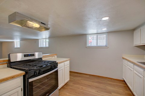 A kitchen with a stove top oven and wooden floors.