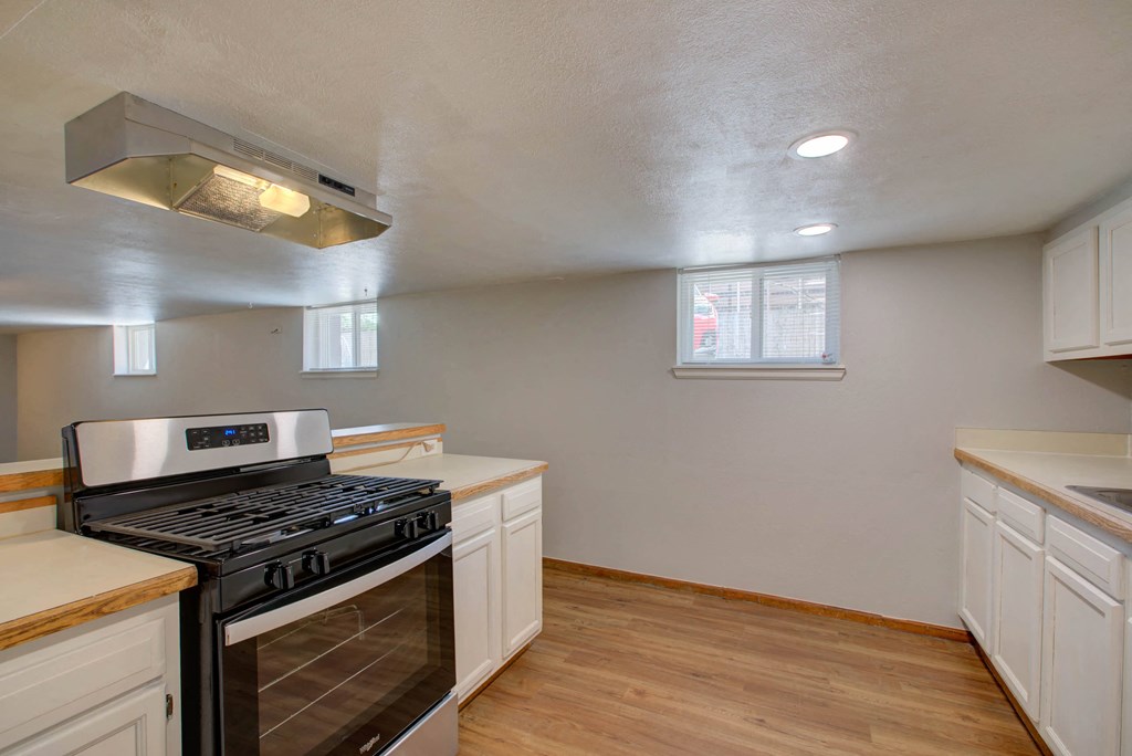 A kitchen with a stove top oven and wooden floors.