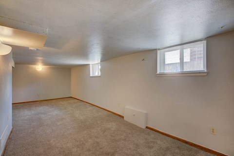 A room with a carpeted floor and a window with blinds.