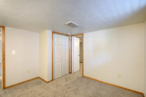 A room with a carpeted floor and a white ceiling with a doorway leading to another room.