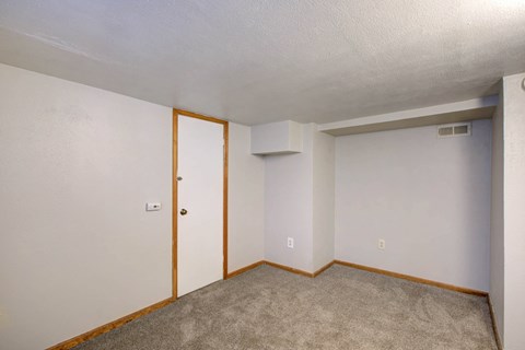 A room with a carpeted floor and a door.