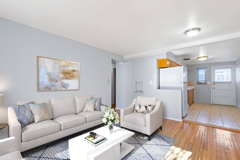 A living room with a white couch and a painting on the wall.
